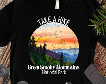 Puede incluir: Camiseta negra con un diseño gráfico blanco que dice "Take a Hike" con una escena de puesta de sol del Parque Nacional de las Grandes Montañas Humeantes.