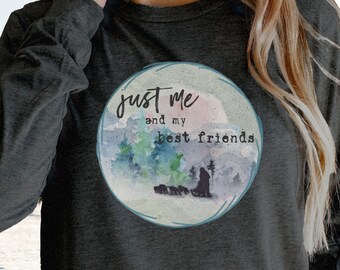 Puede incluir: Una camiseta gris de manga larga con un diseño de acuarela de un paisaje nevado y el texto "Just me and my best friends".