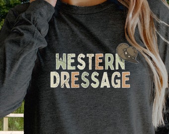 Puede incluir: Una camiseta gris antracita de manga larga con el texto "WESTERN DRESSAGE" en una fuente de estilo vintage. El texto está en tonos de verde, naranja y marrón. Un pequeño gráfico de cabeza de caballo está por encima del texto.