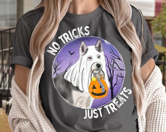 Puede incluir: Una camiseta gris con una ilustración morada y blanca de un perro con un disfraz de fantasma y sosteniendo un cubo de calabaza. El texto "No Tricks Just Treats" está impreso en la camiseta.