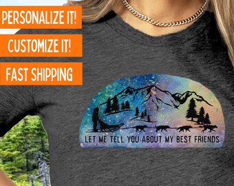 May include: A dark gray t-shirt with a colorful mountain scene and a silhouette of a person with a sled dog team. The text "Let me tell you about my best friends" is printed below the image. The text "Bella Canvas 3001 Short Sleeve Choose from tee shirt, long sleeve, or sweatshirt" is printed at the bottom of the image.