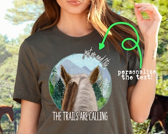 Könnte beinhalten: Ein dunkelgrünes T-Shirt mit kurzen Ärmeln und einem Motiv eines Pferdekopfes in einer Waldlandschaft. Der Text "Just me and the trails" und "The trails are calling" ist auf dem Shirt aufgedruckt. Das Shirt ist in den Ausführungen Kurzarm, Langarm und Sweatshirt erhältlich.