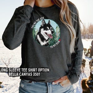 Puede incluir: Una camiseta gris de manga larga con una ilustraci&oacute;n de un perro husky negro y blanco. El perro est&aacute; dentro de un c&iacute;rculo con &aacute;rboles verdes y el texto "You're the gee to my haw" en blanco.