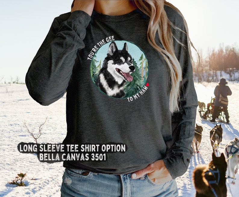 Puede incluir: Una camiseta gris de manga larga con una ilustraci&oacute;n de un perro husky negro y blanco. El perro est&aacute; dentro de un c&iacute;rculo con &aacute;rboles verdes y el texto "You're the gee to my haw" en blanco.