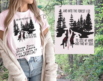 Puede incluir: Una camiseta rosa con un gráfico en blanco y negro de una escena de bosque con el texto "And into the forest I go to lose my mind and find my soul". El texto está en negro y rojo. La camiseta está disponible en manga corta, manga larga o sudadera.