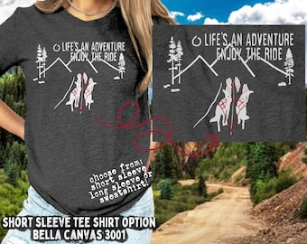 May include: A gray short-sleeved t-shirt with a white graphic of two wolves running up a mountain with the text "Life's an adventure, enjoy the ride".