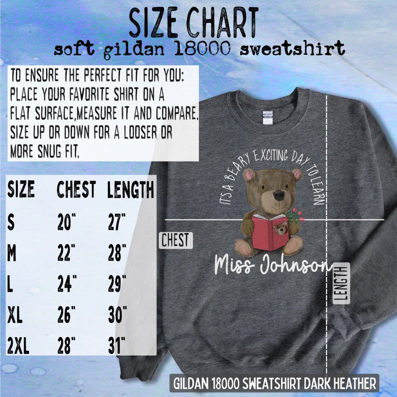 Op de afbeelding: Maattabel voor een donker heather grijs Gildan 18000 sweatshirt. De tabel toont borst- en lengtemaat in inches voor maten S, M, L, XL en 2XL. De afbeelding toont ook een beer die een rood boek draagt en een shirt met de tekst "It's a Beary Exciting Day to Learn" en "Miss Johnson".