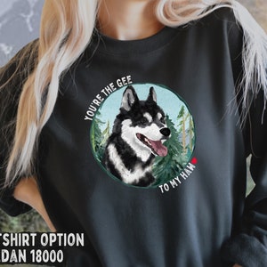 Puede incluir: Sudadera negra con un gr&aacute;fico de un perro husky negro y blanco en una escena de bosque. El texto "You're the Gee to my Haw" est&aacute; impreso alrededor del perro.