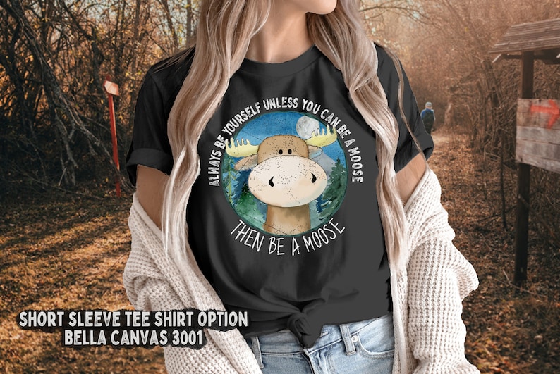 May include: Black short-sleeved t-shirt with a moose illustration and the text "Always be yourself unless you can be a moose then be a moose".