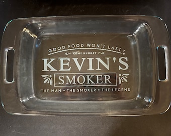 May include: A clear glass baking dish with handles. The dish has an etched design that says "Good food won't last, come hungry. Kevin's Smoker. The man, the smoker, the legend."