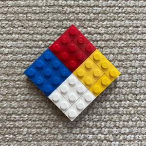 May include: A square made of 16 Lego bricks, arranged in a pattern of four colors: red, blue, white, and yellow.