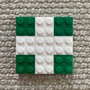 May include: A 3x3 grid of LEGO bricks, alternating between green and white. Each brick has the word "LEGO" printed on it.