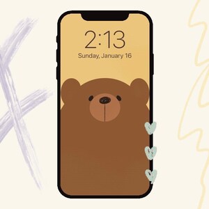 May include: A smartphone with a brown bear illustration on the screen. The time is 2:13 and the date is Sunday, January 16. There are three small, light blue hearts on the right side of the screen.