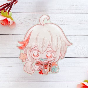 May include: A light pink anime-style character acrylic charm with a chibi design. The charm features a character with light pink hair, red accents, and a small bow. The charm is surrounded by small flowers and leaves.