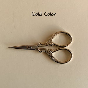 May include: Gold-colored small scissors with an ornate design.