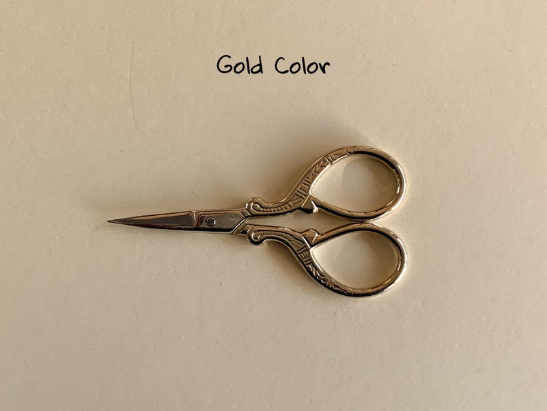 May include: Gold-colored small scissors with an ornate design.