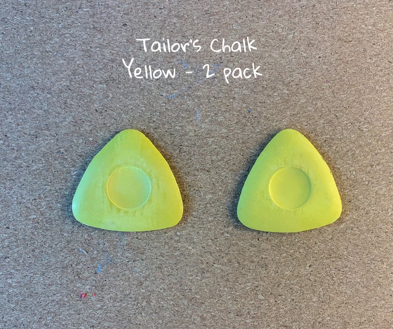 May include: Two yellow tailor's chalk triangles, each with a round center, labeled "Tailor's Chalk Yellow - 2 pack".