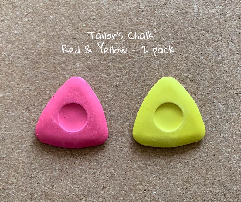 May include: Two triangular tailor's chalk pieces, one red and one yellow, with a round hole in the center. "Tailor's Chalk Red & Yellow - 2 pack" is written above the chalk.