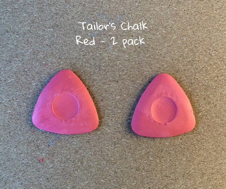 May include: Two red tailor's chalk triangles, each with a round hole in the center. The text "Tailor's Chalk Red - 2 pack" is written above the chalk.