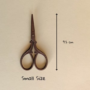 May include: Small, ornate, brown metal scissors with a decorative design. The scissors are 9.2 inches long.