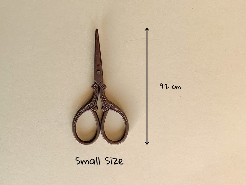 May include: Small, ornate, brown metal scissors with a decorative design. The scissors are 9.2 inches long.