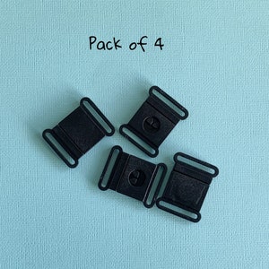 Pu&ograve; includere: Quattro fibbie a sgancio laterale in plastica nera su sfondo azzurro. Ogni fibbia ha una forma rettangolare con un design curvo e un meccanismo di rilascio centrale. Il testo "Pack of 4" si trova nell'angolo in alto a sinistra.