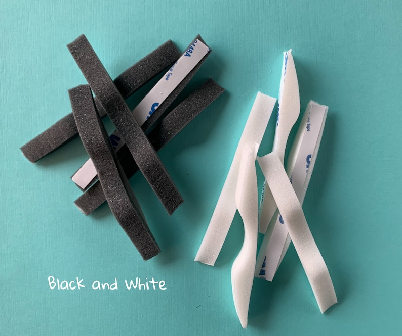 Peut inclure: Bandes de mousse noires et blanches avec un dos adh&eacute;sif. Les bandes mesurent environ 1,2 cm de large et 0,6 cm d'&eacute;paisseur. Le texte "Black and White" est &eacute;crit en blanc sur un fond bleu.