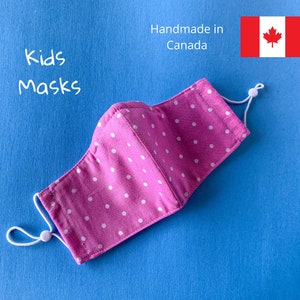 May include: Pink children's face mask with white polka dots and white elastic ear loops. Handmade in Canada.