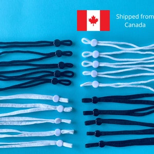 May include: Assortment of black and white elastic cords with adjustable toggles, likely for face masks or similar items. The cords are arranged on a bright blue background. The image includes a Canadian flag.
