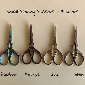 May include: Four pairs of small sewing scissors with ornate handles. The scissors are rainbow, antique, gold, and silver.