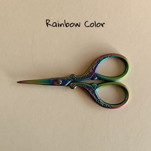 May include: Rainbow colored metal scissors with an ornate design. The scissors have a small screw in the center.