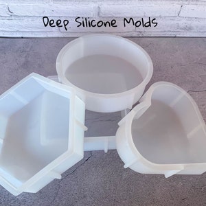 May include: Three white silicone molds for crafting. The molds are shaped like a circle, a heart, and a hexagon.