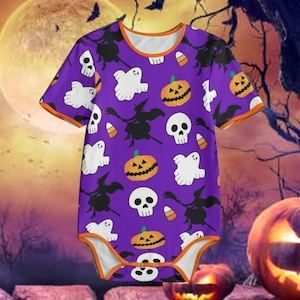 Puede incluir: Body de bebé morado con temática de Halloween y ribete naranja. El body presenta un patrón repetido de fantasmas blancos, calabazas, calaveras, siluetas de brujas y caramelos. El fondo incluye una luna llena y calabazas.