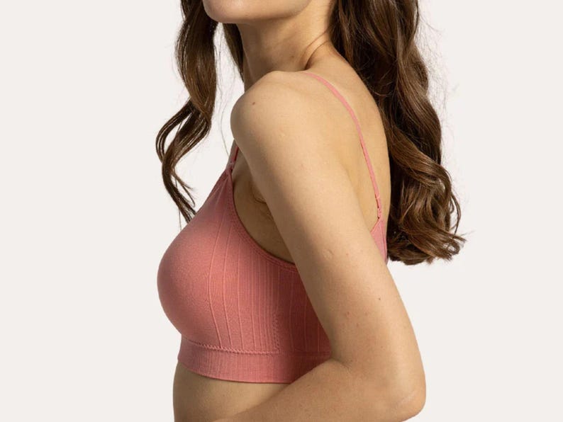 Op de afbeelding: Een geribbelde bralette in oudroze kleur met een naadloze constructie, een brede onderband en dunne verstelbare schouderbandjes. Het kledingstuk is voorzien van een verticaal ribpatroon over het geheel en een ronde halslijn.