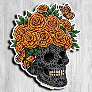 May include: A sticker featuring a black skull with intricate gray filigree patterns, topped with a large cluster of vibrant orange marigold flowers and green leaves, accented by two orange and black monarch butterflies on the sides.