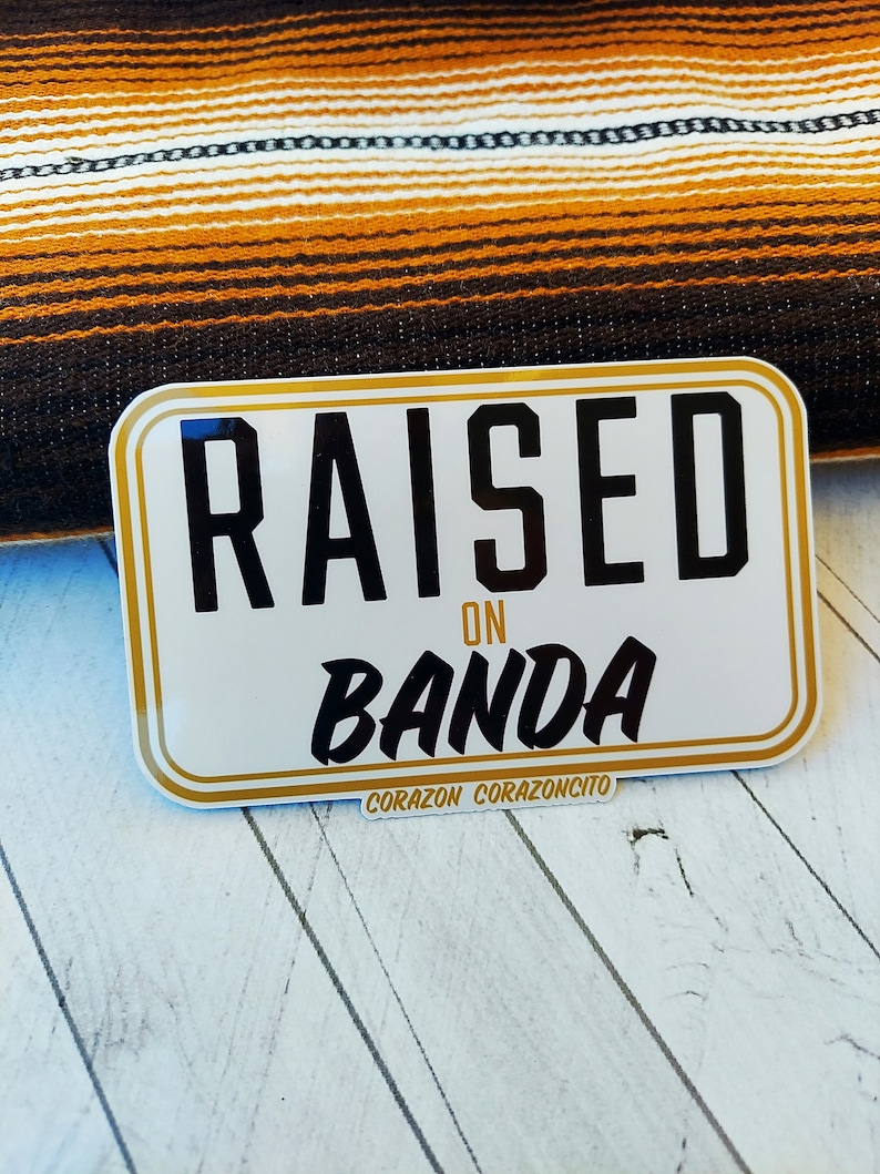 May include: White sticker with gold trim and black text that reads "RAISED ON BANDA" with the words "CORAZON CORAZONCITO" at the bottom.
