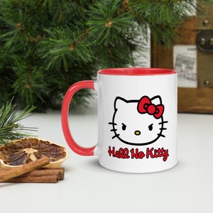 May include: A white ceramic mug with a red rim and handle. The mug features a black and white illustration of Hello Kitty with a red bow, and the text "Hell No Kitty".