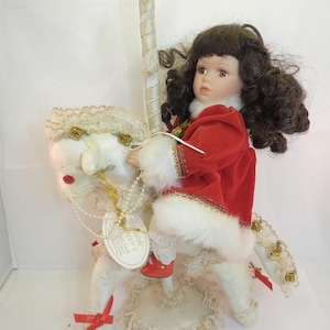 Leonardo doll girl with soft body in Christmas red Dress, seated on horse