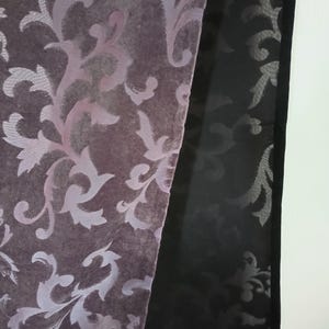 Puede incluir: Un primer plano de una tela morada con un patrón floral blanco. La tela está doblada por la mitad y el borde del pliegue es visible. La tela es suave y lujosa.