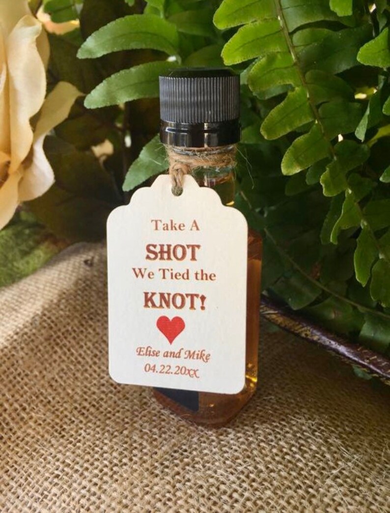 May include: A small bottle of liquor with a white tag that says "Take A SHOT We Tied the KNOT!" with a red heart and the names "Elise and Mike" and the date "04.22.20XX".