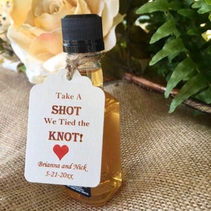 May include: A small bottle of liquor with a white tag that says "Take a Shot We Tied the Knot! Brianna and Nick 5-21-20XX" with a red heart.