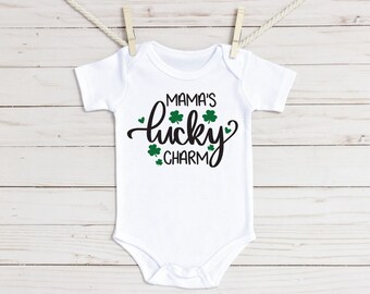 May include: White baby onesie with black text that reads "Mama's lucky charm" and green shamrock graphics.