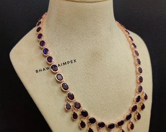 Puede incluir: Un collar de oro rosa con piedras preciosas rojas de forma ovalada y de lágrima. El collar se exhibe en un maniquí. El texto "BHAWANAIMPEX" es visible en el lado izquierdo de la imagen.