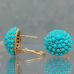 Könnte beinhalten: Ein Paar goldene Ohrringe mit Türkis-Steinen. Die Ohrringe sind rund und haben einen Cluster aus Türkis-Steinen in der Mitte. Die Steine sind in Gold gefasst und die Ohrringe haben ein Tropfen-Design.