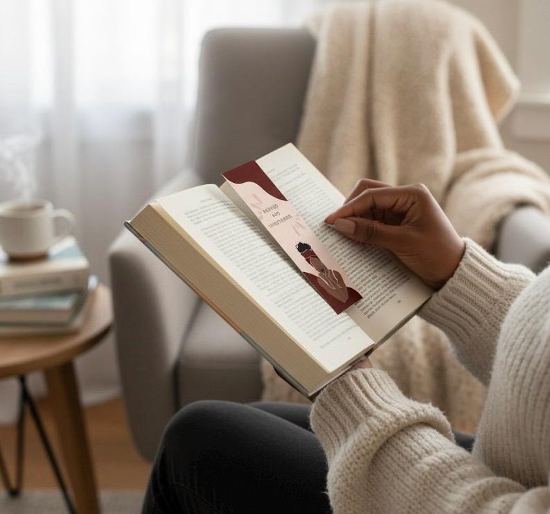 Op de afbeelding: Een bladwijzer met de tekst "Bound and Determined" en een illustratie van een persoon met een hoofddoek is in een open boek geplaatst. De bladwijzer heeft een bordeauxrode en beige kleurstelling. De persoon draagt een cr&egrave;mekleurige trui.