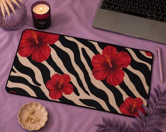 Può includere: Un tappetino da scrivania rettangolare con un motivo ripetuto di vivaci fiori di ibisco rosso su uno sfondo a strisce zebrate nere e beige. Il tappetino presenta una superficie liscia con un bordo nero e un design piatto per la scrivania.
