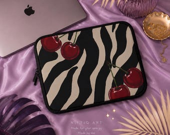 Può includere: Una custodia nera per laptop con un motivo a strisce zebrate e illustrazioni di ciliegie rosse. La custodia ha una cerniera nera e il testo "Niftiq Art" con il motto "Made for your energy. Made by me."