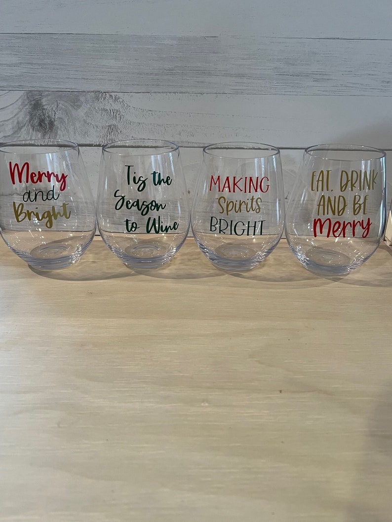 K&ouml;nnte beinhalten: Vier klare, stielose Weingl&auml;ser mit festlichen Texten in Rot, Gold und Gr&uuml;n. Die Gl&auml;ser tragen die Aufschriften: "Merry and Bright", "Tis the Season to Wine", "Making Spirits Bright" und "Eat, Drink and Be Merry".