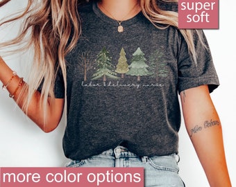 May include: Dark grey heather t-shirt with a graphic of a row of stylized trees with lights and the text "labor & delivery nurse". The shirt is super soft and has a heart icon with the text "super soft" in the top right corner.