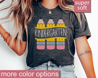 Może przedstawiać: Szary t-shirt w kolorze melanżu z nadrukiem trzech ołówków z napisem "Kindergarten" na płocie. T-shirt jest super miękki.